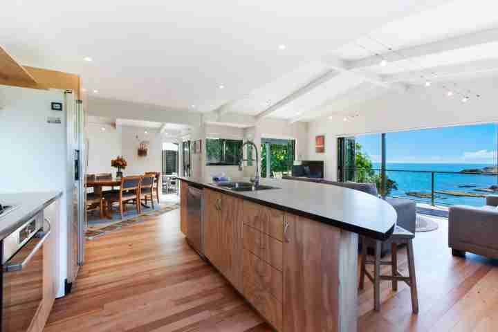 Modern spacious kitchen and lounge area with balcony access and sea view at family beachfront holiday home
