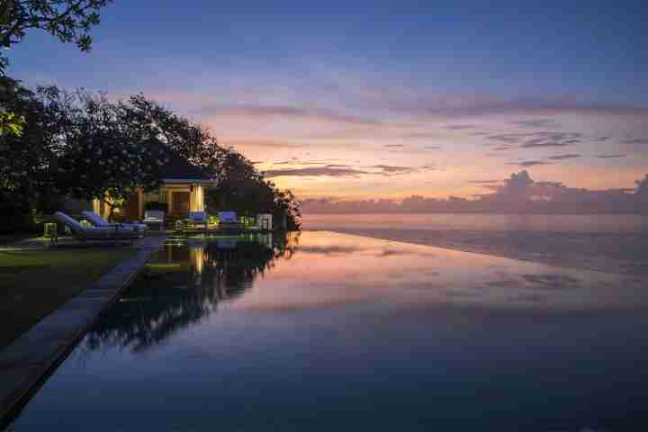 Beautiful Balinese sunset reflection in infinity pool at luxury five star estate Uluwatu