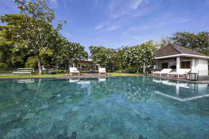 Infinity pool at Uluwatu Estate with private beach access and white loungers