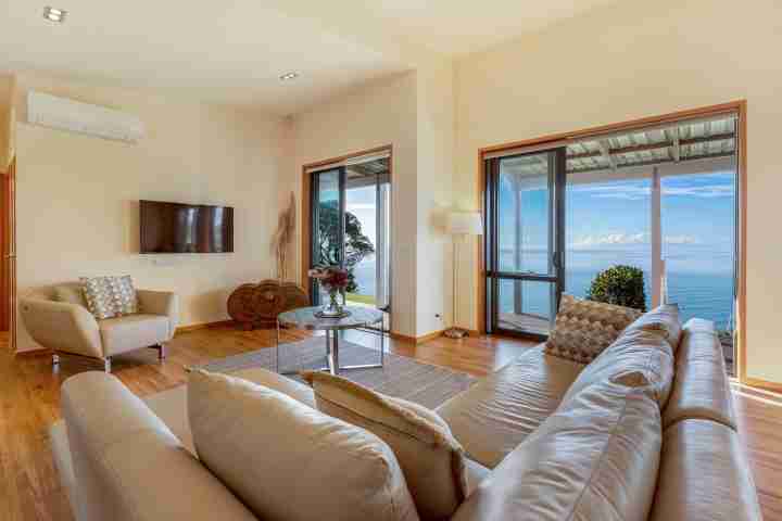 Family living area with outdoor access, sea view and TV at Moeraki