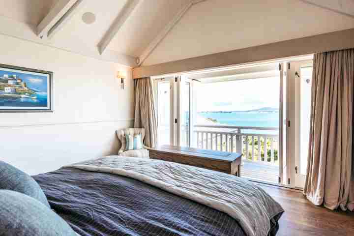 Balcony access and beach view from modern double bedroom at private Waiheke Island estate