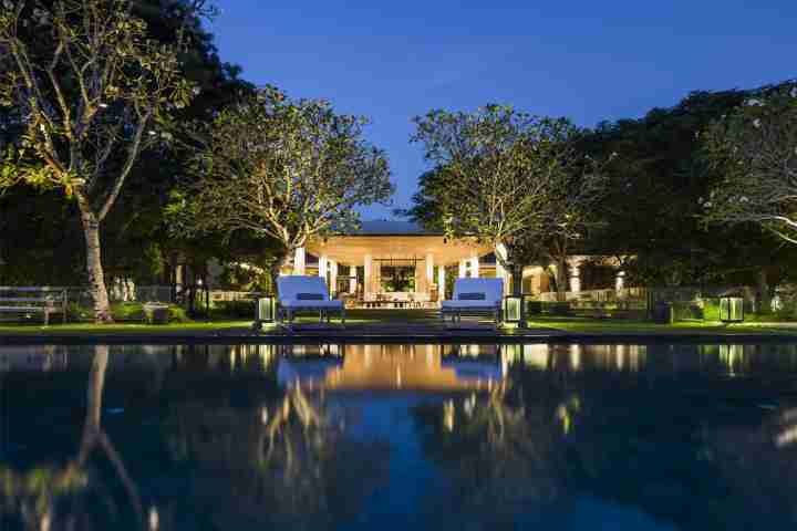 Infinity pool at night with luxury Balinese estate in background