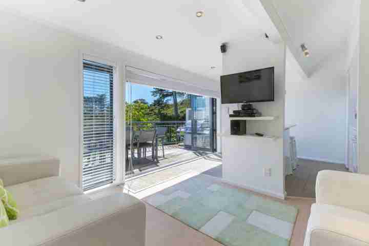 Open plan lounge with TV and access to private deck with sea view