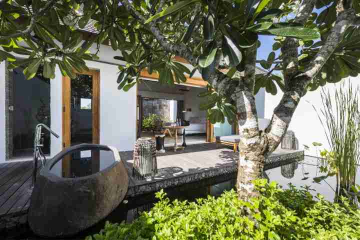 Outdoor living area and bathtub with view of pond