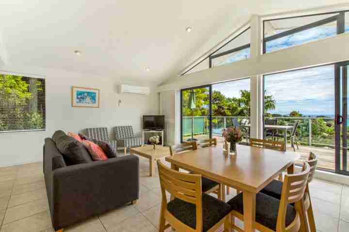 Lounge and dining area onto deck in modern apartment at The Resort, Waiheke