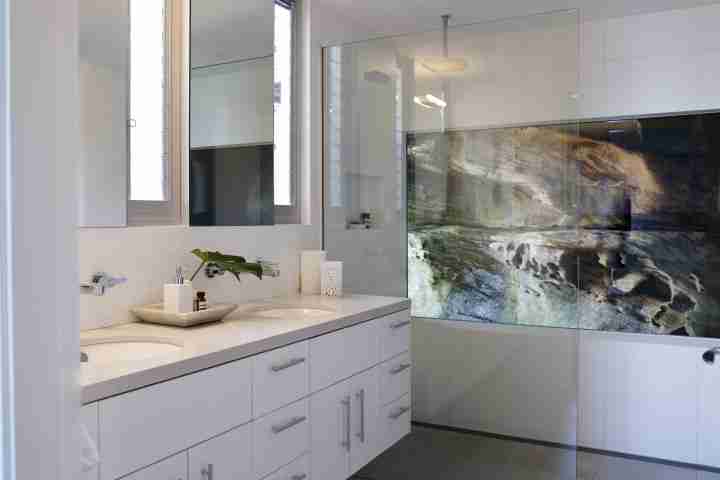 Large walk in shower with view of rock feature, and twin vanities in bathroom at luxury Whale Beach House Amaroo Australia